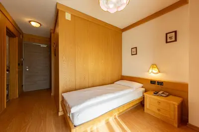 a small bedroom with a bed and a table at Dolomiten Hotel Irma in Canazei