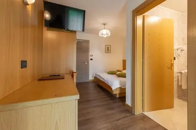 a bedroom with a bed and a television on a wall at Dolomiten Hotel Irma in Canazei