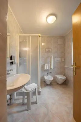 a bathroom with a sink and a shower and a toilet at Dolomiten Hotel Irma in Canazei