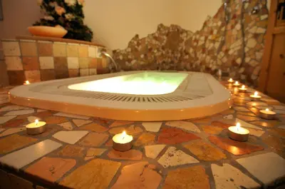 a bath tub with candles on a tiled floor at Garni Hotel Iris in Selva di Val Gardena