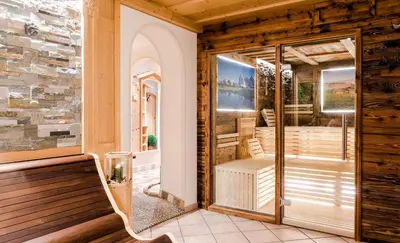 a porch with a bench and a glass door at Garni Hotel Iris in Selva di Val Gardena