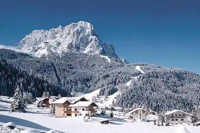 a snow covered mountain with a town in the foreground at Garni Hotel Iris in Selva di Val Gardena