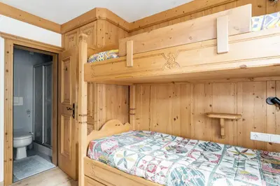 a bedroom with two bunk beds and a bathroom at Aurturist Appartement 185 in San Vigilio Di Marebbe
