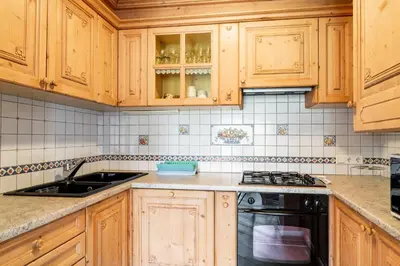 a kitchen with wooden cabinets and a sink and a stove at Aurturist Appartement 185 in San Vigilio Di Marebbe
