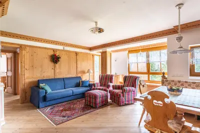 a living room with a blue couch and two chairs at Aurturist Appartement 185 in San Vigilio Di Marebbe