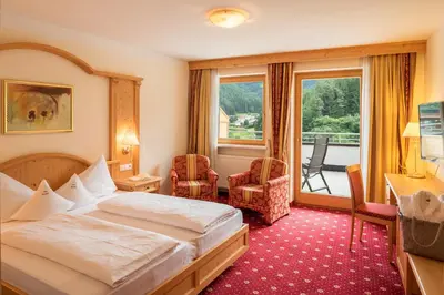 a hotel room with a bed and a balcony at Hotel Kronblick in Chienes