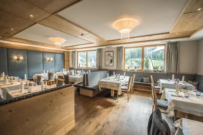 a dining room with tables and chairs and windows at Hotel Kronblick in Chienes