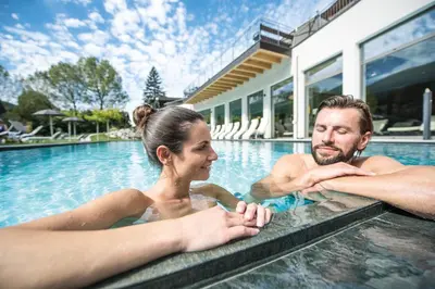 a man and a woman in a swimming pool at Hotel Kronblick in Chienes
