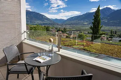 a table and chairs on a balcony with a view at Hotel Törggelehof in Cermes