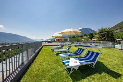 a row of chaise lounges are lined up on a balcony at Hotel Törggelehof in Cermes
