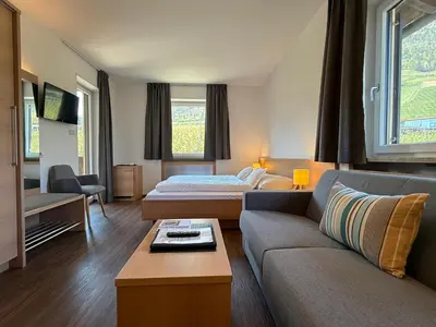 a hotel room with a couch and a bed at Hotel Törggelehof in Cermes