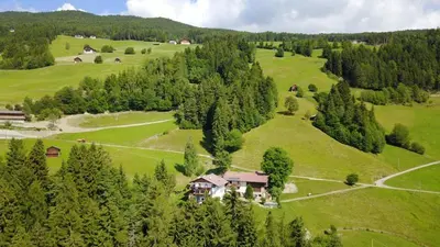 a house in the middle of a green field with trees at Rasiglerhof in Villandro