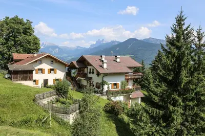 a house on a hill with mountains in the background at Rasiglerhof in Villandro