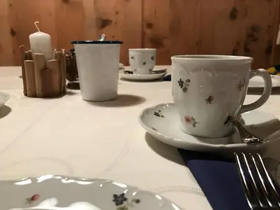 a table with a white cup and saucers and a candle at Agriturismo Maso Larciunei in Selva di Val Gardena