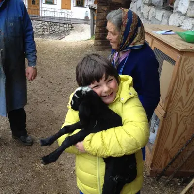 a young child is holding a black goat at Agriturismo Maso Larciunei in Selva di Val Gardena
