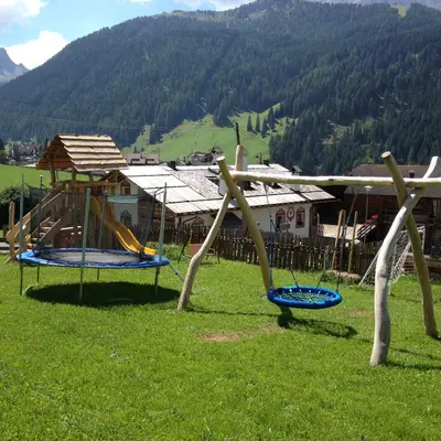 a group of swings in a field with a mountain at Agriturismo Maso Larciunei in Selva di Val Gardena