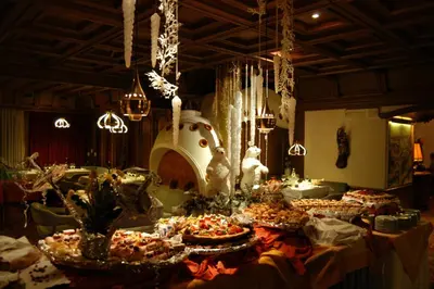 a table with many plates of food in a room at Alpen Hotel Corona in Vigo di Fassa