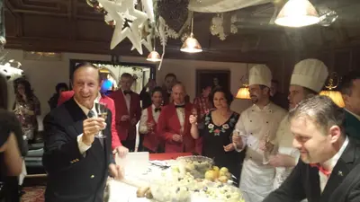 a group of people standing around a table with a cake at Alpen Hotel Corona in Vigo di Fassa
