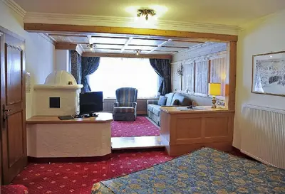 a hotel room with a reception desk and a living room at Alpen Hotel Corona in Vigo di Fassa