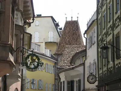 a narrow street with buildings and a clock on a building at Space Nr. 11 in Merano