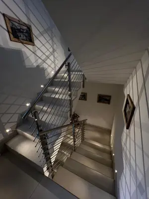 a staircase in a house with a metal railing at Garnì Letizia in Campitello di Fassa