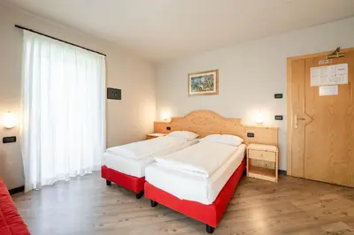 a hotel room with two beds and a window at Garnì Letizia in Campitello di Fassa