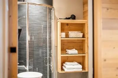 a bathroom with a shower and a sink and towels at Garnì Letizia in Campitello di Fassa