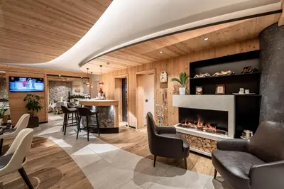 a living room with a fireplace and a bar at Garnì Letizia in Campitello di Fassa