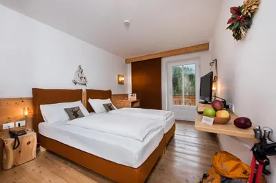a bedroom with a large bed and a television at Small & Lovely Hotel Zaluna in Predazzo