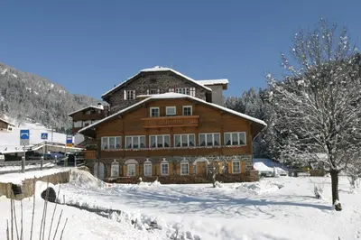 a large wooden building with snow on the ground at Small & Lovely Hotel Zaluna in Predazzo
