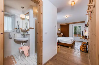 a bathroom with a sink and a bedroom at Small & Lovely Hotel Zaluna in Predazzo
