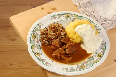 a plate of food with meat and mashed potatoes and gravy at Small & Lovely Hotel Zaluna in Predazzo
