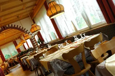 a restaurant with a long table in a room with windows at Small & Lovely Hotel Zaluna in Predazzo