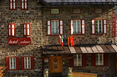 a building with red windows and a sign on it at Small & Lovely Hotel Zaluna in Predazzo