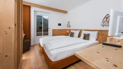 a bedroom with a large white bed and a desk at Small & Lovely Hotel Zaluna in Predazzo