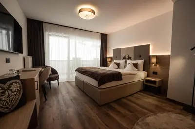 a bedroom with a bed and a wall with a lamp at Freina Mountain Lifestyle Hotel in Selva di Val Gardena