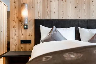 a bed with a black head board and white pillows at Cadepunt The Dolomites Lodge in Selva di Val Gardena