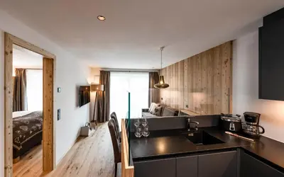 a kitchen with a sink and a room with a bed at Cadepunt The Dolomites Lodge in Selva di Val Gardena