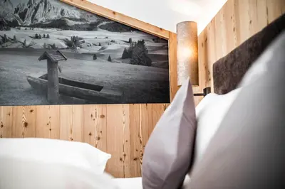 a bedroom with a bed with a picture on the wall at Cadepunt The Dolomites Lodge in Selva di Val Gardena