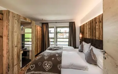 a bedroom with a large bed and a window at Cadepunt The Dolomites Lodge in Selva di Val Gardena