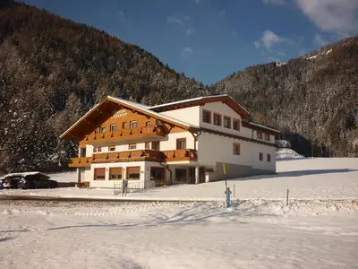 a building in the snow in front of a mountain at Pension Wiesenhof in Campo di Trens