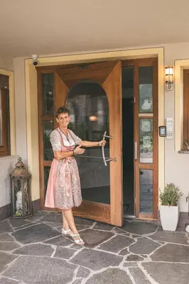 a woman standing outside of a door holding an umbrella at Pension Wiesenhof in Campo di Trens