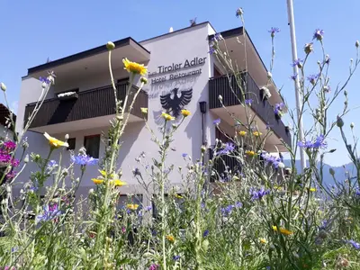 a building with flowers in front of it at Hotel Zum Tiroler Adler in Tirolo
