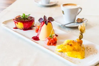 a plate of food on a table with a cup of coffee at Hotel Zum Tiroler Adler in Tirolo