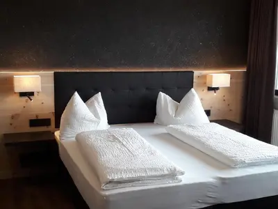 a bed with two white pillows and two lamps at Hotel Zum Tiroler Adler in Tirolo