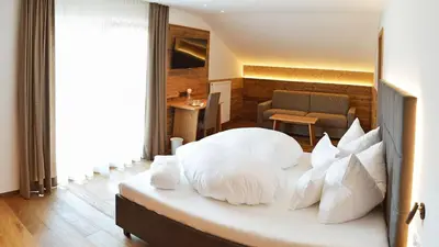 a bedroom with a large bed with white pillows at Hotel Trenker in Braies
