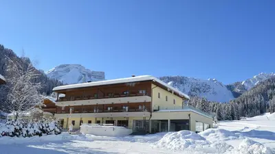a large building in the snow with mountains in the background at Hotel Trenker in Braies