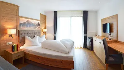 a bedroom with a large white bed with a window at Hotel Trenker in Braies