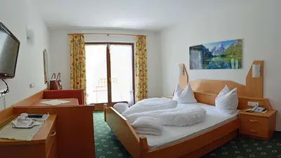 a hotel room with a bed and a desk at Hotel Trenker in Braies