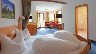 a bedroom with a large bed with white pillows at Hotel Trenker in Braies